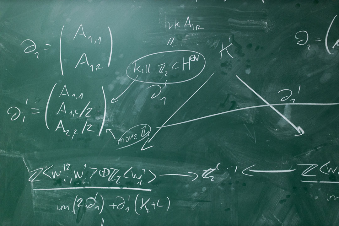 A green chalkboard covered in mathematical equations