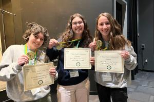 Three students smiling and holding up certificates from the Calculus Olympiad